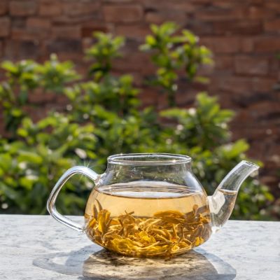 A transparent teapot filed with green tea.