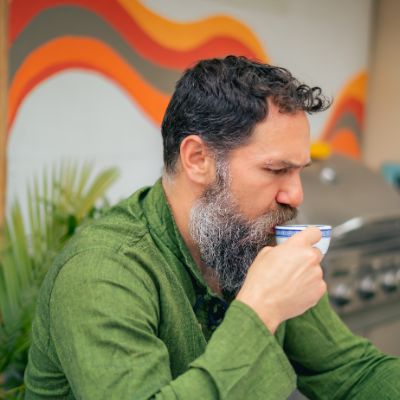 A man sipping on a cup of chamomile tea. 