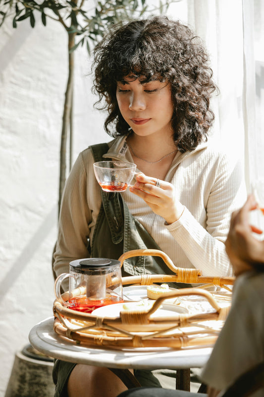 A woman with curly hair drinking decaf tea. 