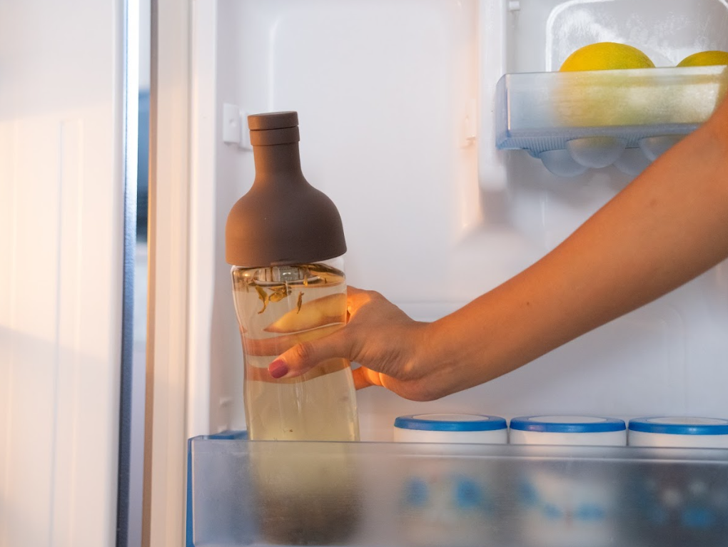 A cold-brew infuser bottle made of borosilicate glass being taken our from the fridge.  