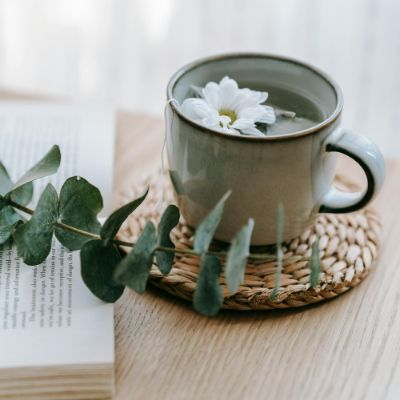 A cup of white tea with caffeine with a white flower floating on the surface. 