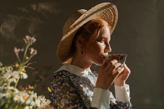 A woman enjoying a delicious cup of tea next to her bed in the morning. 