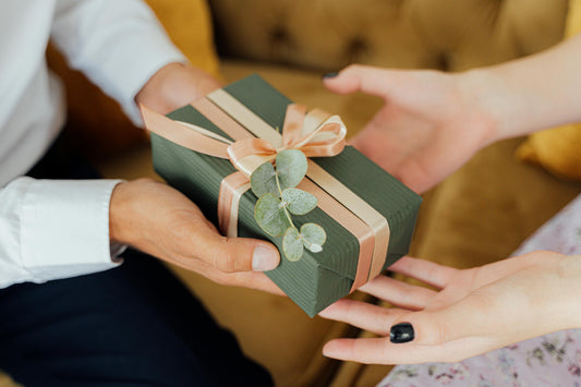 A person giving a wrapped tea gift set to a loved one. 