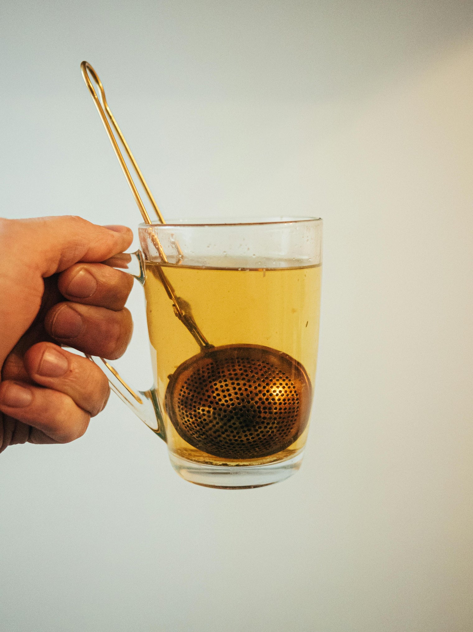 A tea infuser inside a transparent cup. 